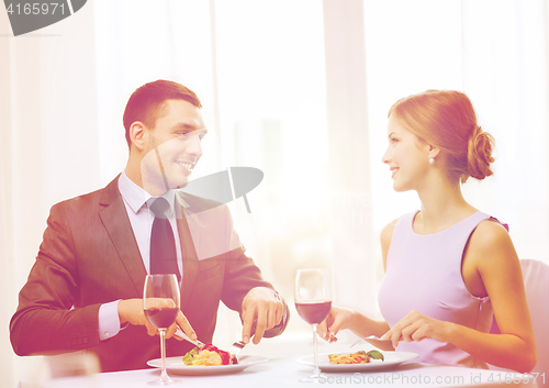 Image of smiling couple eating main course at restaurant