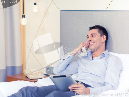 Image of businessman with tablet pc and phone in hotel room