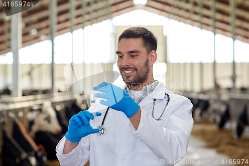 Image of veterinarian with syringe vaccinating cows on farm