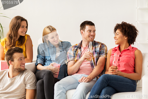 Image of happy friends with popcorn and beer at home