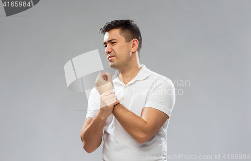 Image of unhappy man suffering from pain in hand