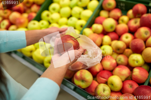 Image of woman with bag buying apples at grocery store