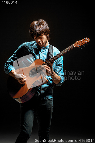 Image of Cool guy standing with guitar on dark background