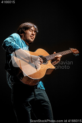 Image of Cool guy standing with guitar on dark background