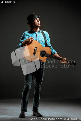 Image of Cool guy standing with guitar on dark background