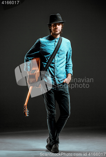 Image of Cool guy standing with guitar on dark background