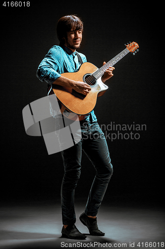 Image of Cool guy standing with guitar on dark background