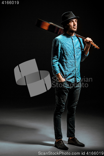 Image of Cool guy standing with guitar on dark background