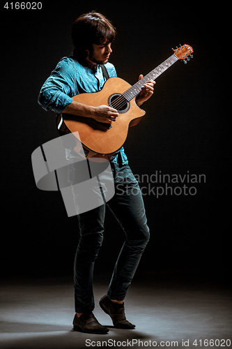 Image of Cool guy standing with guitar on dark background