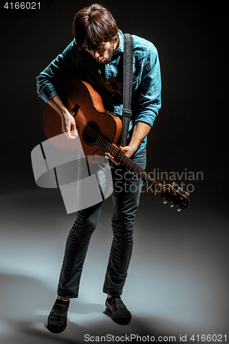 Image of Cool guy standing with guitar on dark background