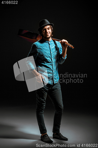 Image of Cool guy standing with guitar on dark background