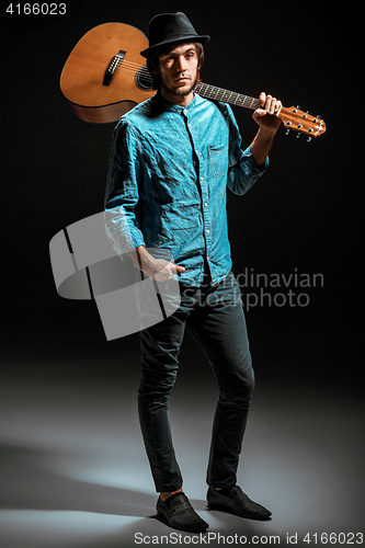 Image of Cool guy standing with guitar on dark background