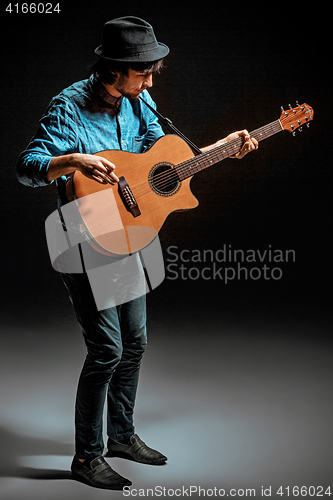 Image of Cool guy standing with guitar on dark background