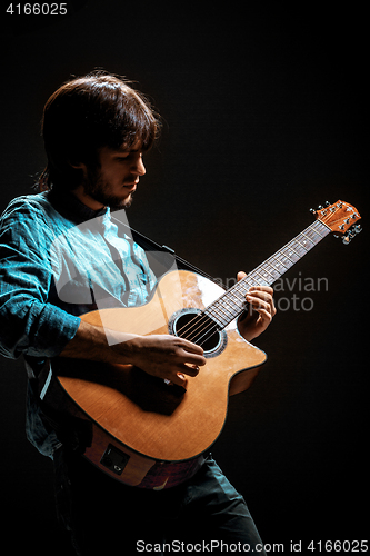 Image of Cool guy standing with guitar on dark background