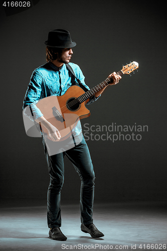 Image of Cool guy standing with guitar on dark background