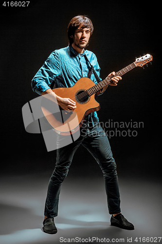 Image of Cool guy standing with guitar on dark background