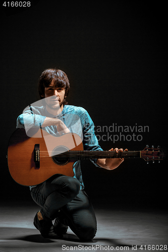 Image of Cool guy standing with guitar on dark background