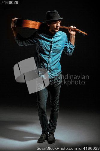 Image of Cool guy standing with guitar on dark background