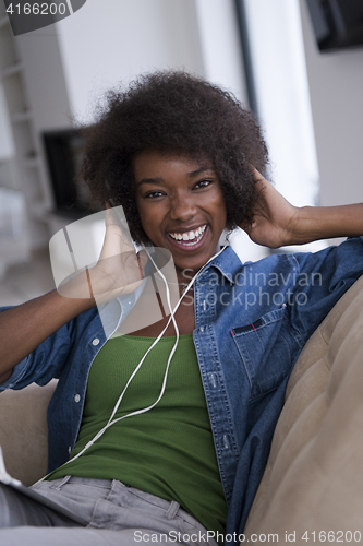 Image of African american woman at home in chair with tablet and head pho