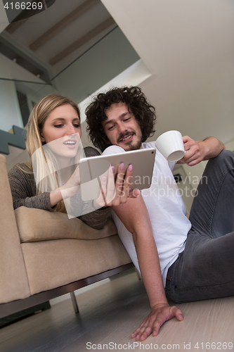 Image of couple relaxing at  home with tablet computers