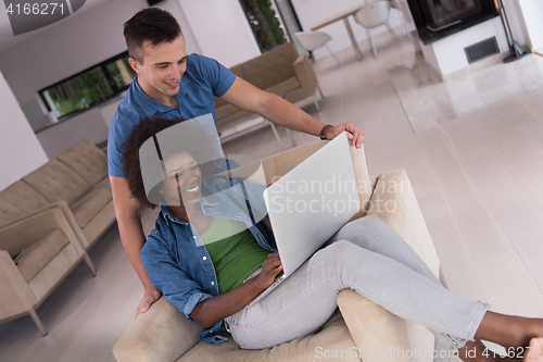 Image of multiethnic couple on an armchair with a laptop