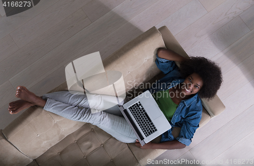 Image of African American woman using laptop on sofa top view