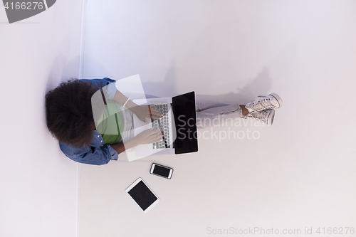 Image of african american woman sitting on floor with laptop top view