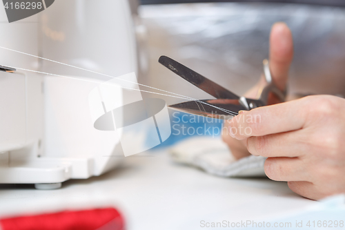 Image of Girl with scissors cuts thread