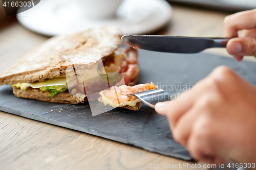 Image of person eating salmon panini sandwich at restaurant