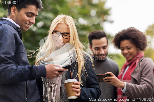 Image of happy friends with smartphone and coffee outdoors