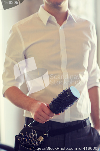 Image of close up of male stylist with brush at salon