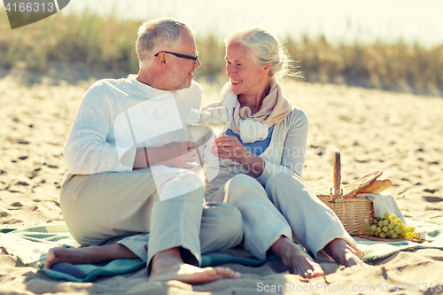 Image of happy senior couple having picnic on summer beach