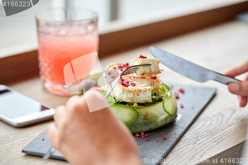 Image of woman eating goat cheese salad at restaurant