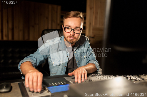 Image of man at mixing console in music recording studio