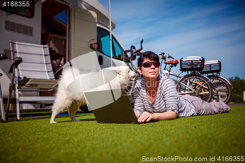 Image of Woman on the grass with a dog looking at a laptop