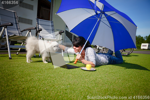 Image of Woman on the grass with a dog looking at a laptop