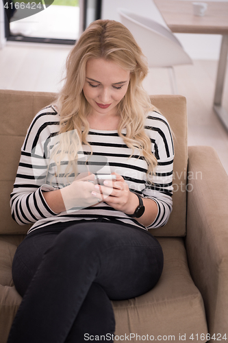 Image of woman sitting on sofa with mobile phone