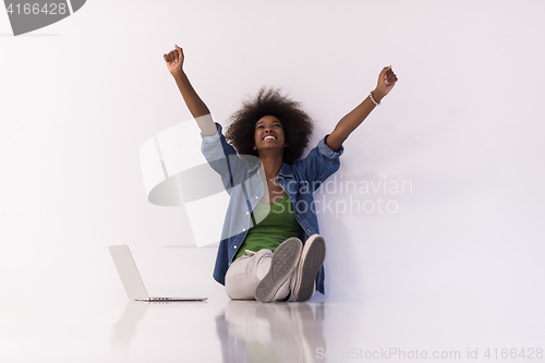 Image of african american woman sitting on floor with laptop