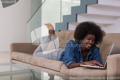 Image of African American woman using laptop on sofa