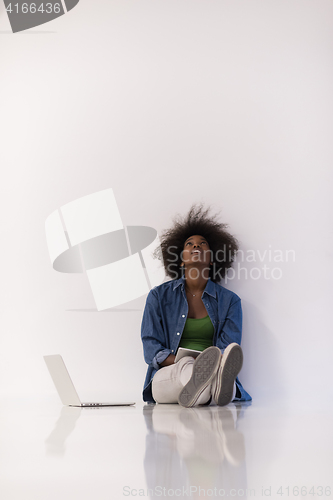 Image of african american woman sitting on floor with laptop