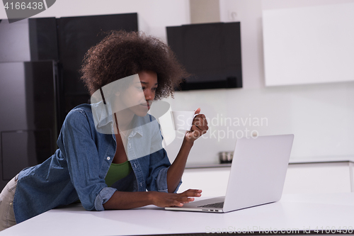 Image of smiling black woman in modern kitchen