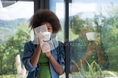 Image of African American woman drinking coffee looking out the window