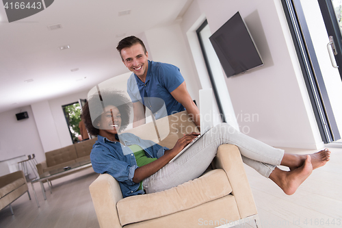 Image of multiethnic couple on an armchair with a laptop