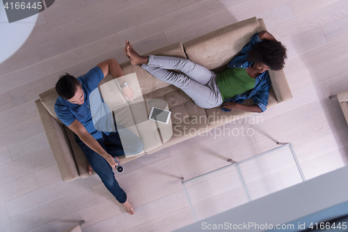 Image of multiethnic couple relaxes in the living room top view