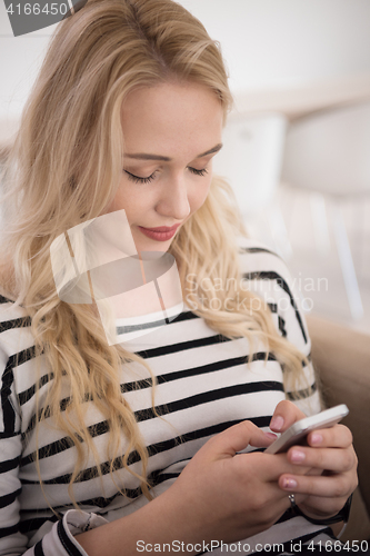 Image of woman sitting on sofa with mobile phone