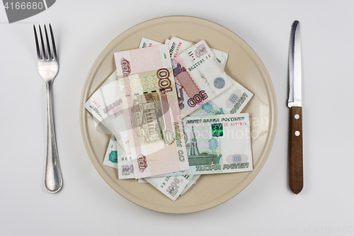 Image of On the plate is a lot of money Russian rubles, lie next to utensils top view