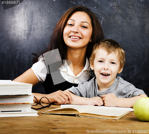 Image of little cute boy with teacher in classroom at desk