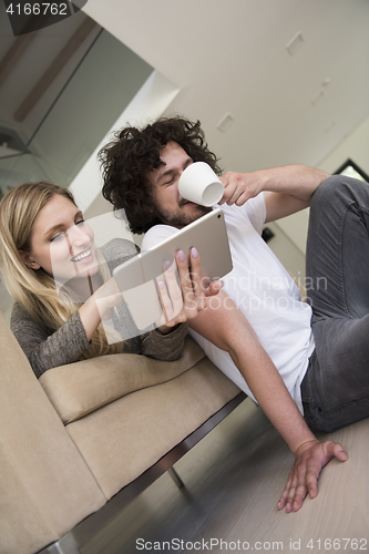 Image of couple relaxing at  home with tablet computers