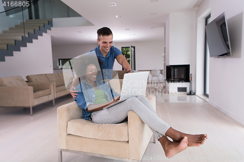 Image of multiethnic couple on an armchair with a laptop