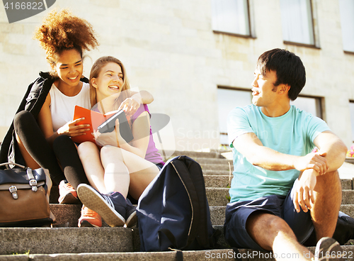 Image of cute group of teenages at the building of university with books huggings, back to school